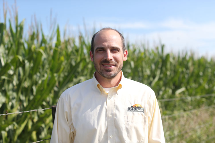Portrait of Adam Daniel standing next to a corn field.
